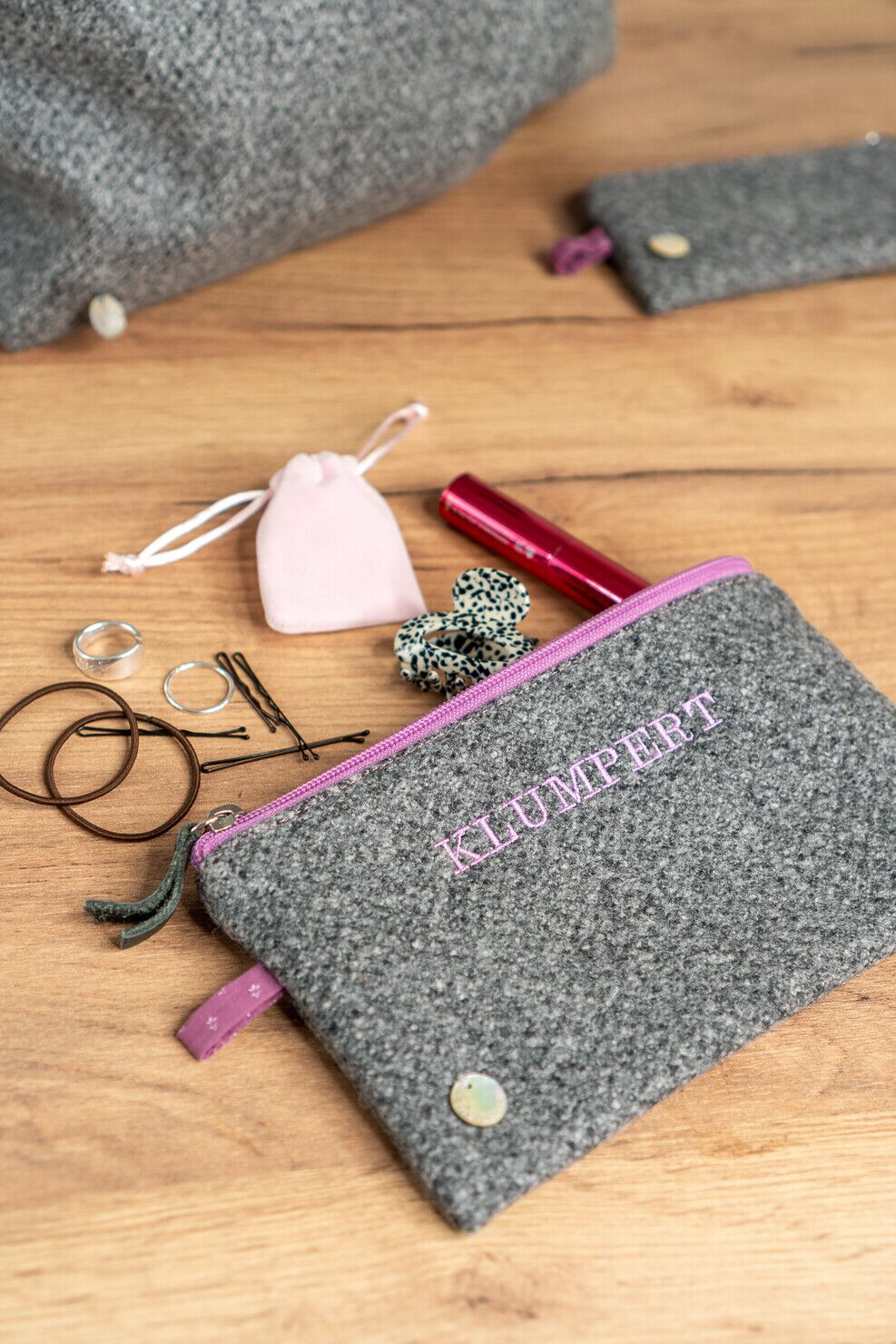 Etui MARA aus Loden in Grau mit rosa Akzenten und witziger Stickerei „Klumpert“.